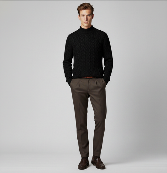 Man wearing a black turtleneck sweater and brown pants on a gray background